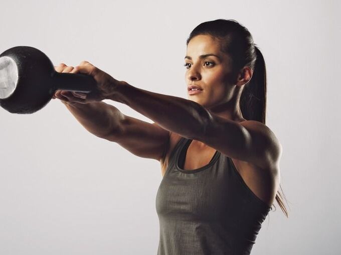 Egy lány gyakorlatot hajt végre, hogy kettlebell segítségével megnagyobbítsa a melleit